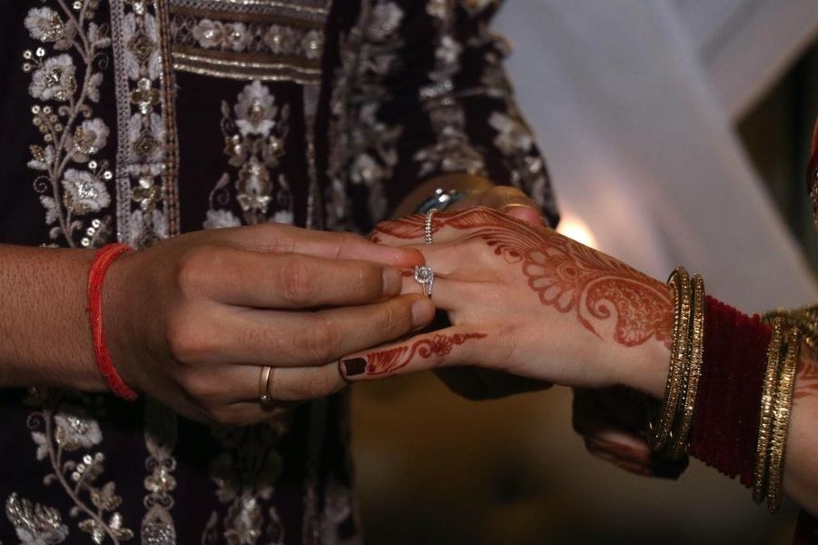 Engagement ring being slipped onto a hand decorated with mehendi